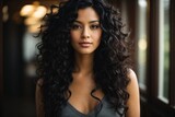 Beautiful woman with long curly black hair, smirking.