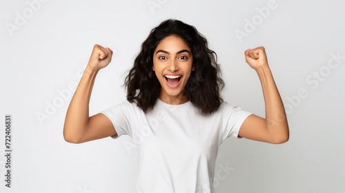 Success Celebration. Girl with Smartphone Fist Pump - Casual Attire, White Wall Background - Exciting Reward Message Received
