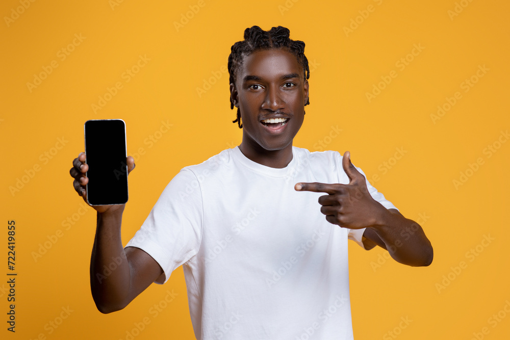 Happy Young Black Man Pointing At Smartphone With Blank Screen In Hand Happy Young Black Man Pointing At Smartphone With Blank Screen In Hand