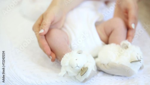 Mother is throw together newborn babys leg with lamb baby-shoes. photo