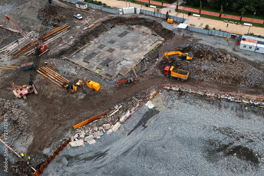 Aerial view of construction site with excavators and dump trucks during earthworks and building foundation construction. Construction industry Aerial view of construction site with excavators and dump trucks during earthworks and building foundation construction. Construction industry