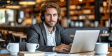 Man Working at Table With Laptop and Headphones
