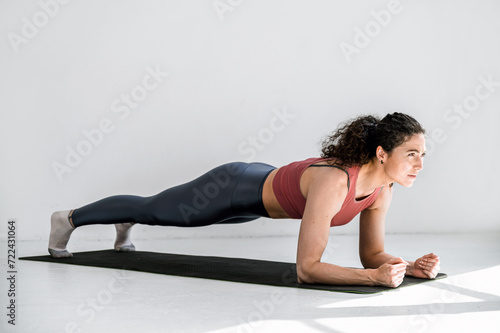 Sporty woman exercising at gym, warming up and doing elbow plank on mat