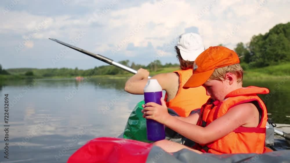 Boy sit and hold bottle with water and woman row in canoe on river Boy sit and hold bottle with water and woman row in canoe on river