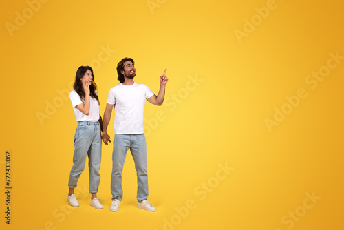 Joyful woman and man in casual white tops and blue jeans holding hands