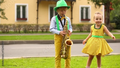 Boy and girl on the street, boy playing saxophone and girl dancing photo