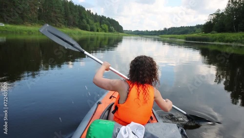 Back of rowing woman in orange life-jackets swimming in canoe  photo