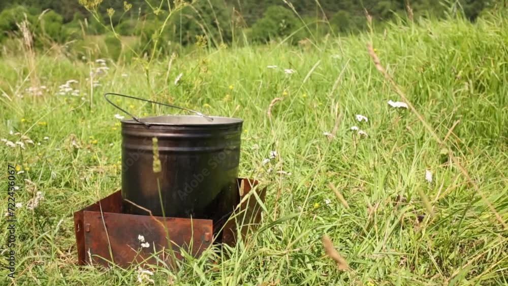 Pot on gas-burner with iron barrier on green grass on lawn. Pot on gas-burner with iron barrier on green grass on lawn.
