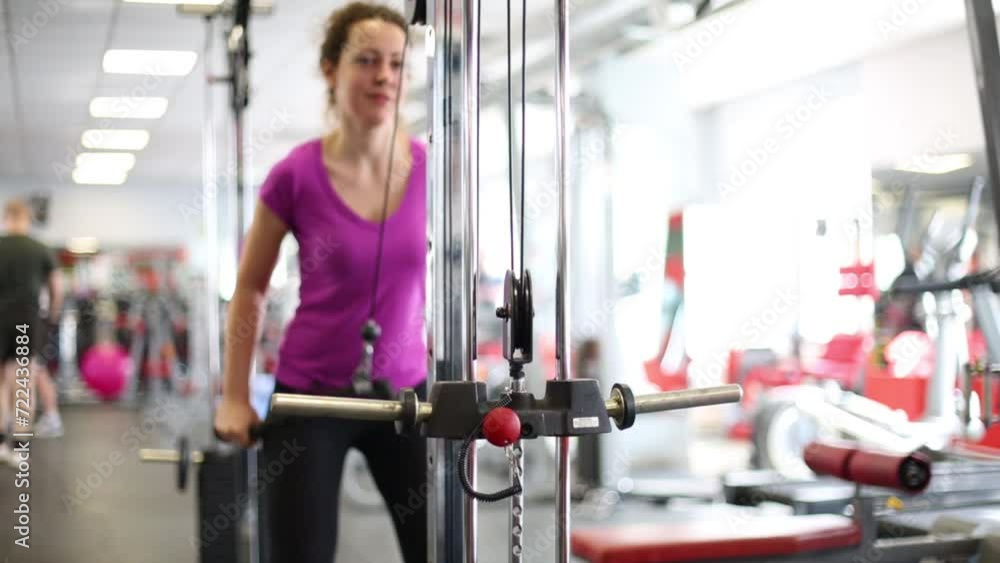 Curly woman is doing exercise on sport equipment at the gym. Curly woman is doing exercise on sport equipment at the gym.