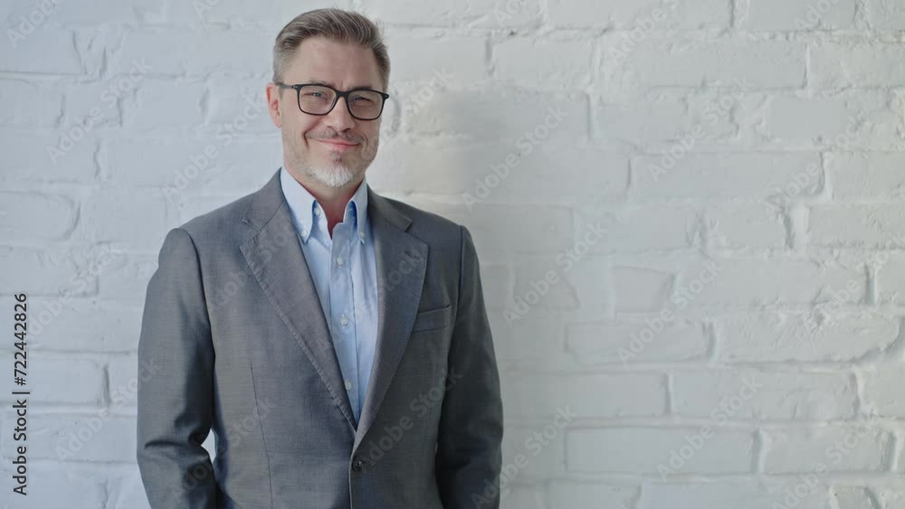 Middle age businessman in business casual. Entrepreneur in jacket. Mid adult, mature age man, happy smiling. Portrait against white brick wall with copy space. Middle age businessman in business casual. Entrepreneur in jacket. Mid adult, mature age man, happy smiling. Portrait against white brick wall with copy space.