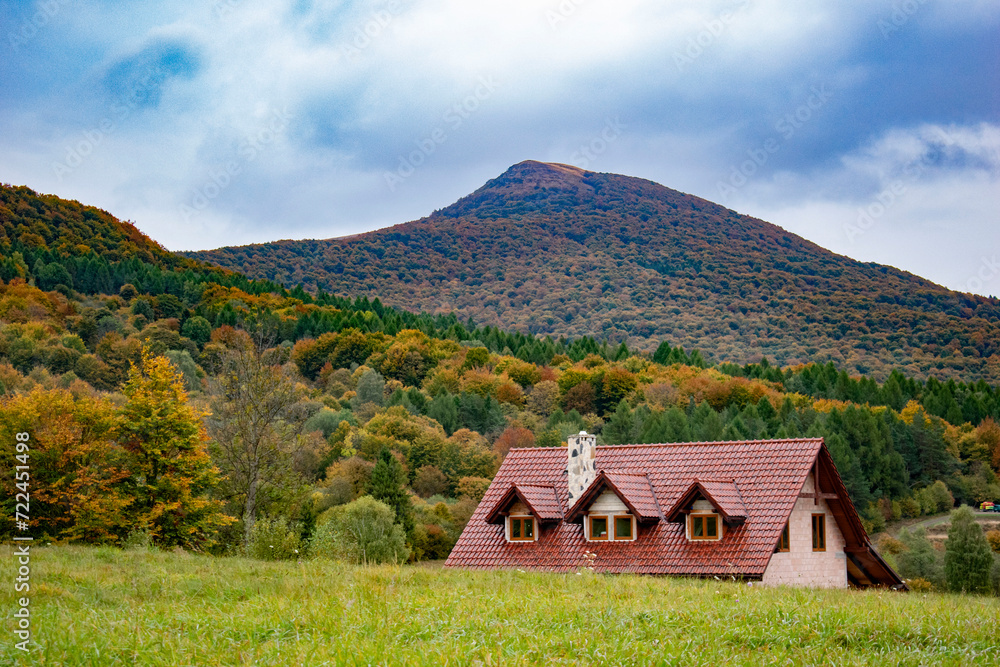 a picturesque, colorful view of the mountains in the autumn aura and a house in the background