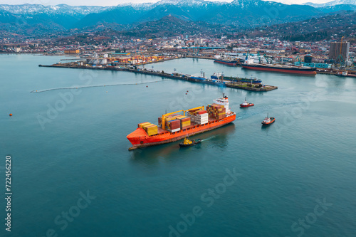 Aerial view of cargo ship carrying containers for import and export, business logistic and transportation sail out sea port in Batumi, Georgia. Drone view. Freight shipping