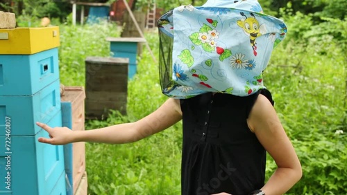 Girl in hat with net gingerly touch beehive in Izmailovo Apiary.  photo