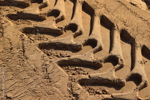 Wheel tracks in the wet sand close up. wheel tread mark on a dirt road. Tire prints on a brown sandy road.  wheel tread mark on a dirt road. Top view.