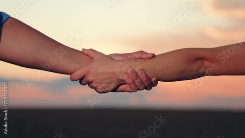 Handshake agreed. Handshake of two businessmen colleagues against background of sun, silhouette of two hands in nature. Business through handshake. Conclusion of deal. Business people shake hands, sky