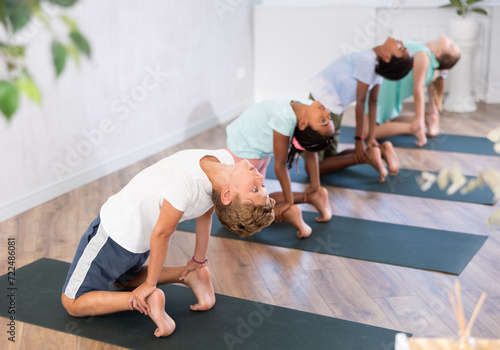 Group of preteen children practicing yoga lesson at sport club or studio
