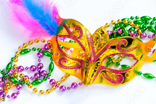 Golden carnival mask and colorful beads on white background. Closeup symbol of Mardi Gras or Fat Tuesday.