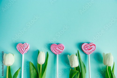 Tulips and lolipop in shape of heart on a blue background. Valentine's day concept, banner format. photo