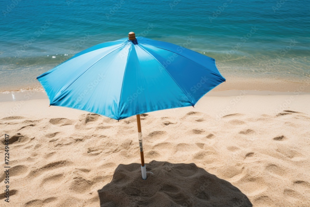 A blue umbrella resting on a sandy beach. Perfect for beach vacations and relaxation