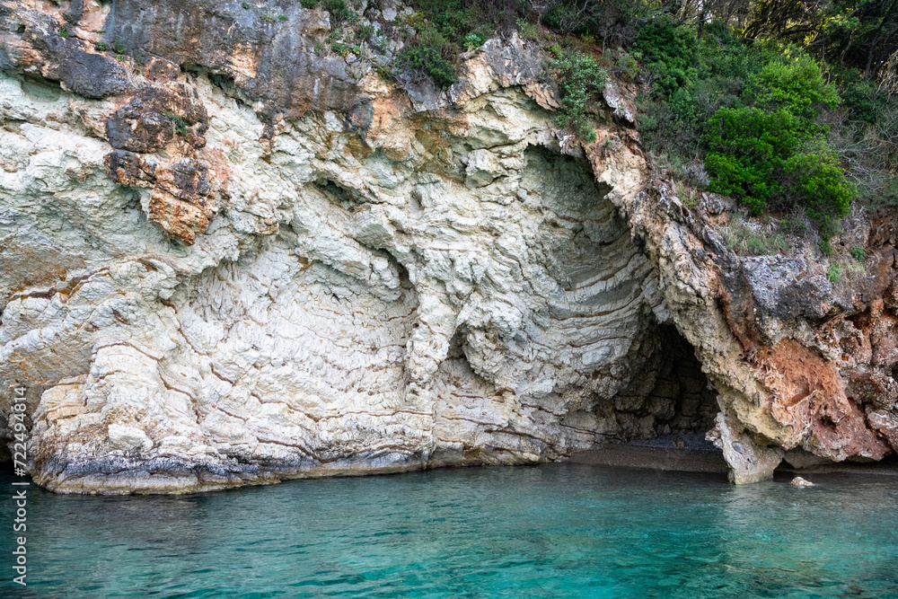 Scenic landscape of Island of Corfu, Greece, western shoreline with cliffs and caves at beach and water line of turquoise or deep blue water with breath taking limestone formations