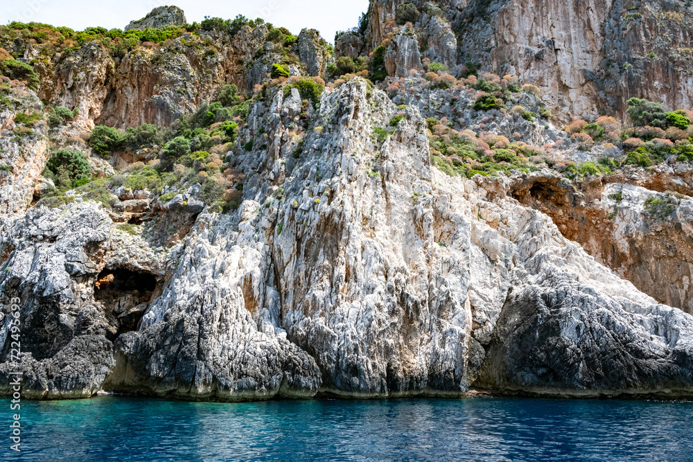 Scenic landscape of Island of Corfu, Greece, western shoreline with cliffs and caves at beach and water line of turquoise or deep blue water with breath taking limestone formations