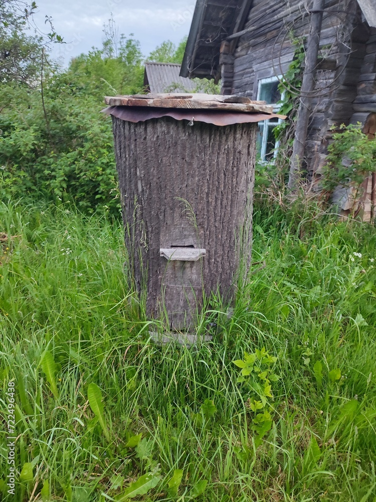 Obraz premium an old abandoned beehive made from a tree trunk stands on a field near a barn in the village