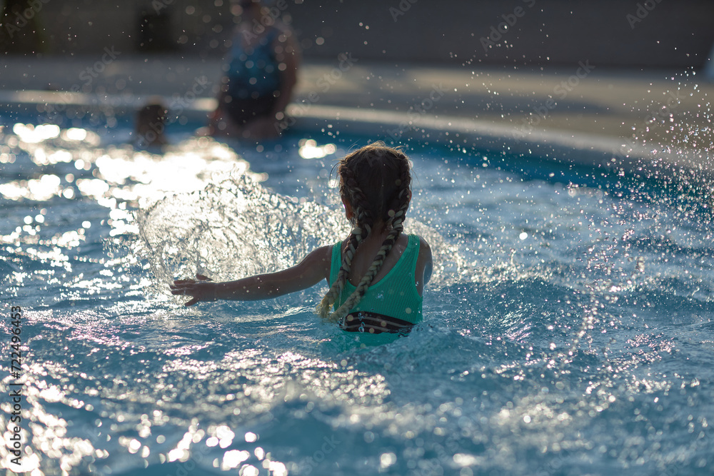 a 4-year-old girl in the pool rides down a slide, splashes of joy and the charm of the child emphasizes the beauty of these frames a 4-year-old girl in the pool rides down a slide, splashes of joy and the charm of the child emphasizes the beauty of these frames