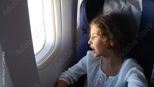 Girl yawn and watch in illuminator in flying airplane close up photo