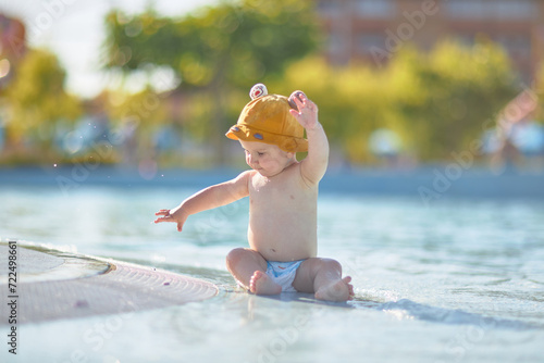 a little half a year old, a baby baby crawling on the water, smiling, outdoors, in a panama hat, in diapers, in the sun at the resort.
