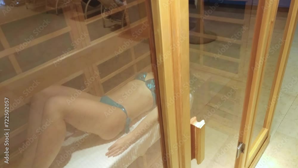 Body of woman lying in infrared wood sauna near swimming pool close up Body of woman lying in infrared wood sauna near swimming pool close up