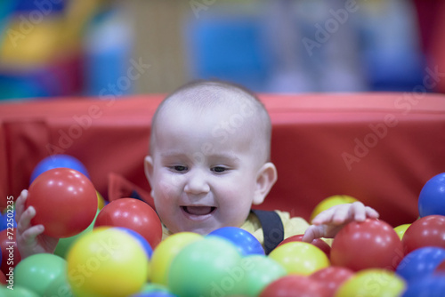 a one-year-old child, a boy, a joyful kid in toys, a lot of balls