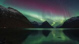 Northern lights, in the calm water surface of a lake surrounded by snow-capped mountains. Concept for travel posters, postcards, print, background material. copy space