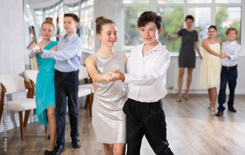 Fototapeta premium Dancing couples - teenagers in festive clothes dance the Viennese waltz in the dance studio