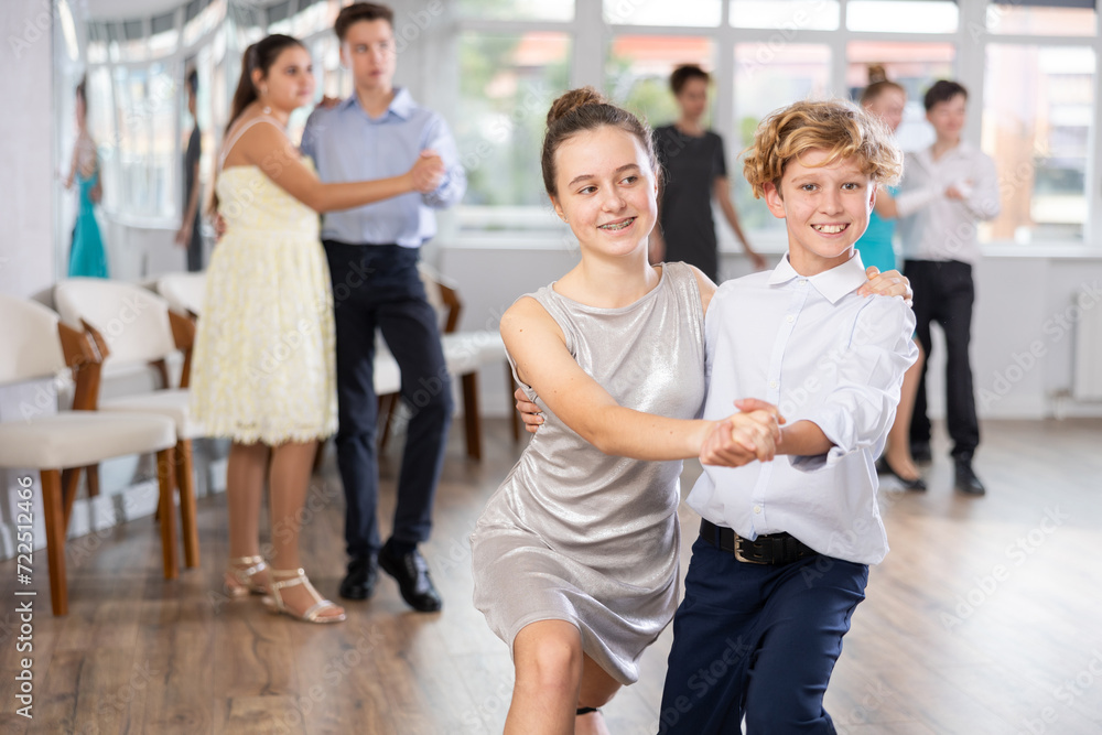 Fototapeta premium Teen guy and girl perform movements and dance hustle in pairs under guidance of woman coach. Classes in dance studio, choreography