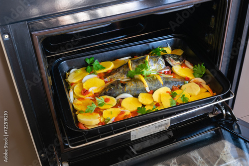 Delicious raw mackerel with potatoes and tomato, onion, lemon and spices in a dish prepared to put in the oven photo