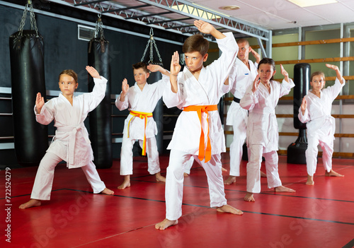 Focused children trying new martial moves in a practice during karate class in gym