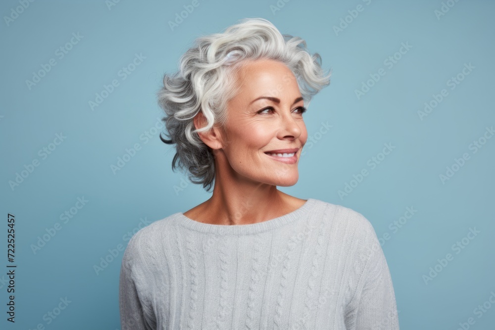 Portrait of a happy senior woman with grey hair on blue background