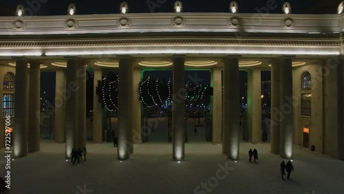 People walk through entrance gate of Gorky Park at winter evening photo