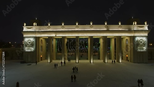 People walk by alley of Gorky Park near entrance gate at winter  photo