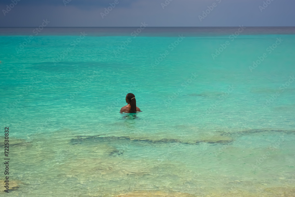 A photo of a young African Caribbean man with dreadlocks refreshing in the azure blue sea. 