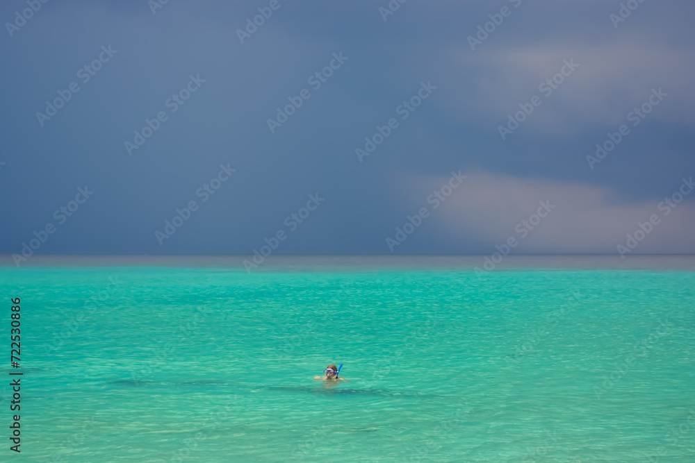 A person snorkelling in Caribbean sea during rain. Beautiful tropical colours. 