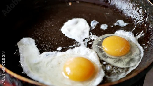 cooking at home.  organic ingredients for a healthy lifestyle.  scrambled eggs for breakfast.  eggs are fried in an old frying pan.  Cracking an egg into a pan and sprinkling it with a pinch of salt.
