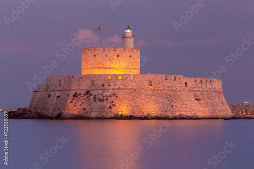 Old stone lighthouse in Fort St. Nicholas in Rhodes at sunset.