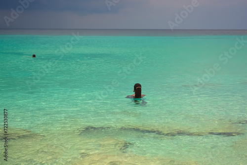 A photo of a young African Caribbean man with dreadlocks refreshing in the azure blue sea. 