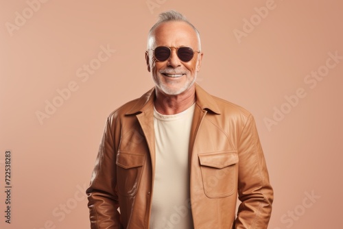 Portrait of smiling senior man in sunglasses. Isolated on brown background.