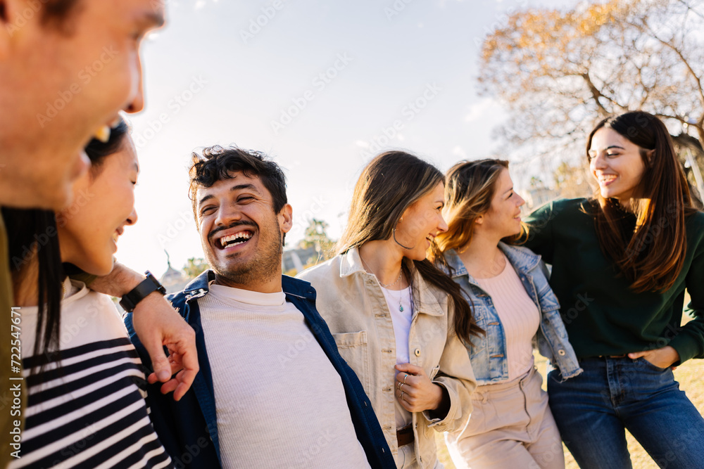 Happy diverse group of young adult multi-ethnic friends standing embraced and smiling in an urban park. Friendship and diversity concept. Happy diverse group of young adult multi-ethnic friends standing embraced and smiling in an urban park. Friendship and diversity concept.