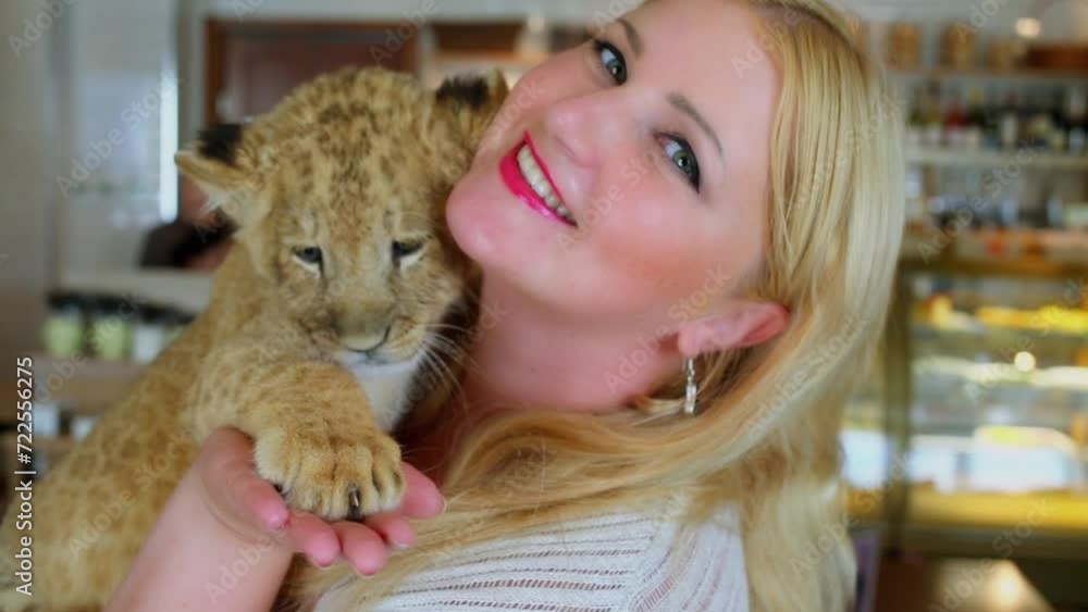 Blonde smiles and holds calf of lion close on her hands Blonde smiles and holds calf of lion close on her hands