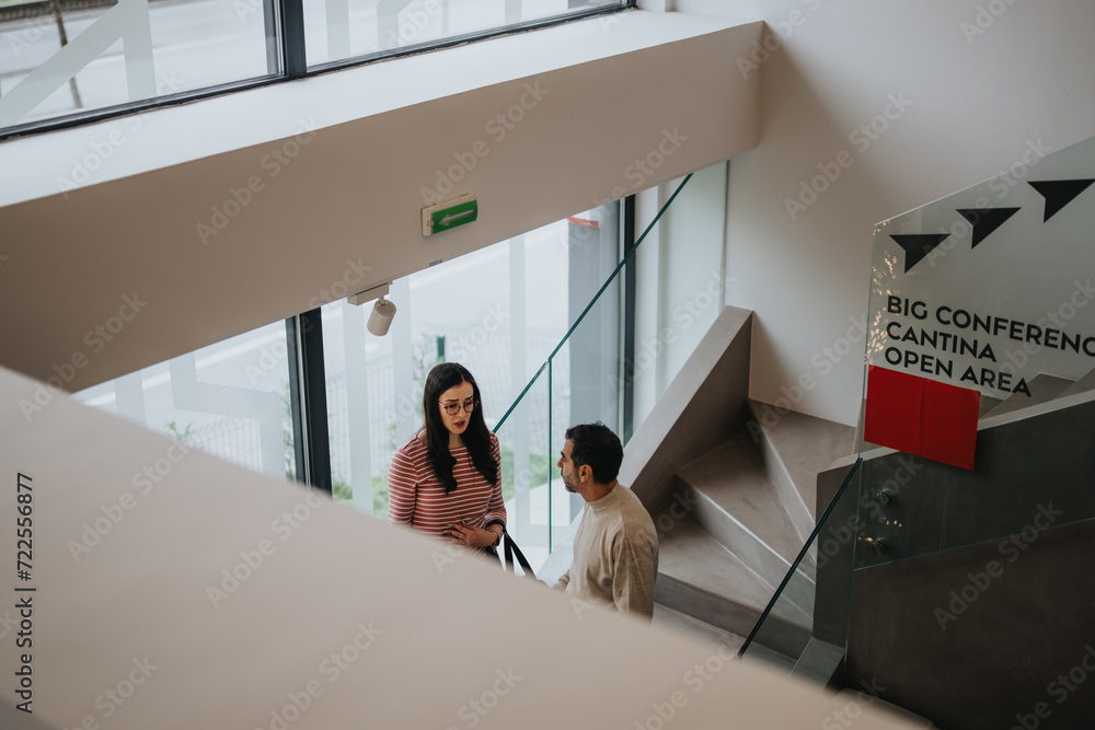 Fototapeta premium Two colleagues in casual attire engaging in conversation in office building.