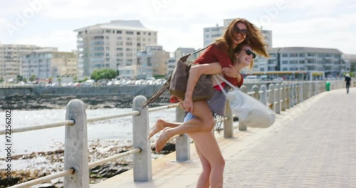 Friends, piggyback and laughing on vacation at ocean, spin and bonding together on weekend trip. Happy women, support and playing fun game on summer holiday, freedom and traveling to beach or sea