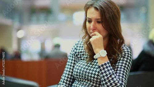 Sad young woman cries and looks around in hall of trade center photo